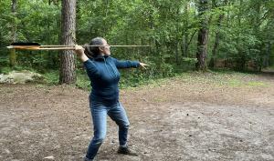 Photographie d'une femme effectuant un tir à l'aide d'une reconstitution de propulseur préhistorique