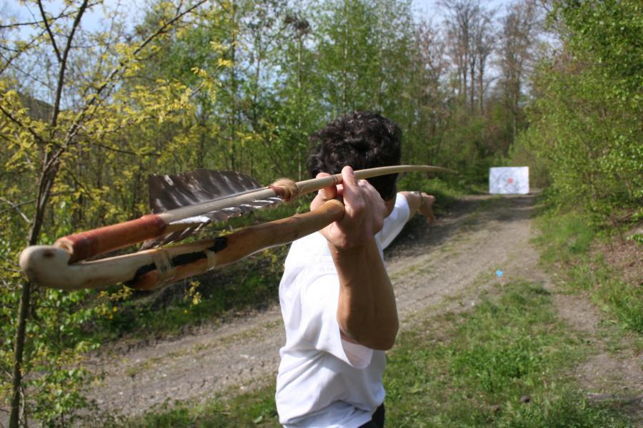Photo couleur. Un compétiteur de tir préhistorique se prépare à lancer sa sagaie vers une cible.